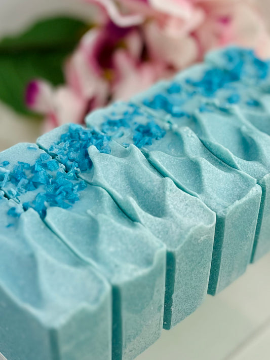 Blue soap bar with decorative blue salt top on a blurred floral background