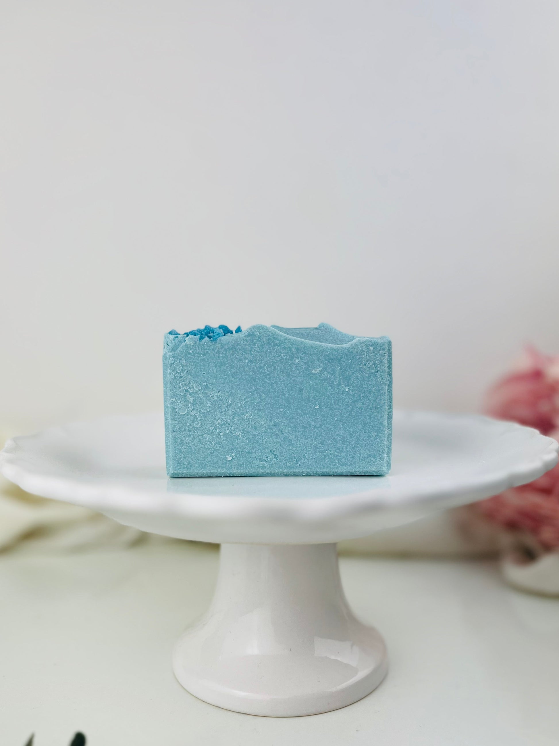 Blue salt soap bar on a white pedestal with a neutral background
